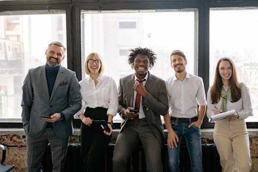 A diverse group of business professionals smiling and standing together in the office.