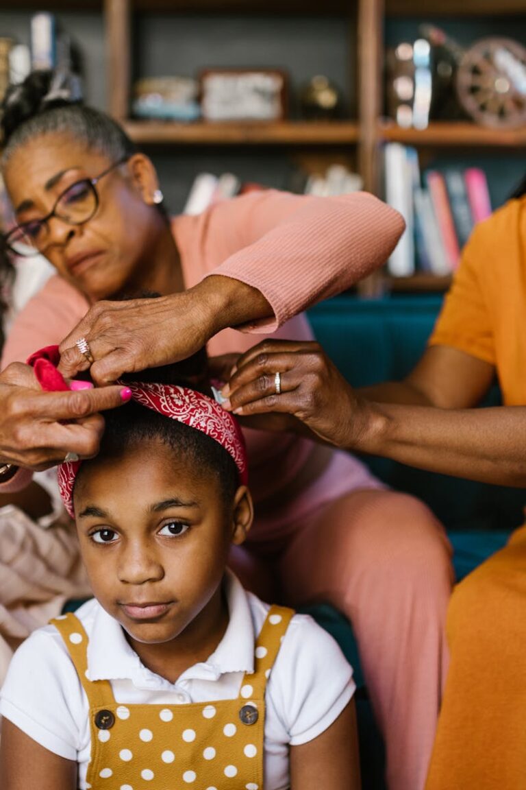 A loving family moment as women style a young girl's hair indoors.